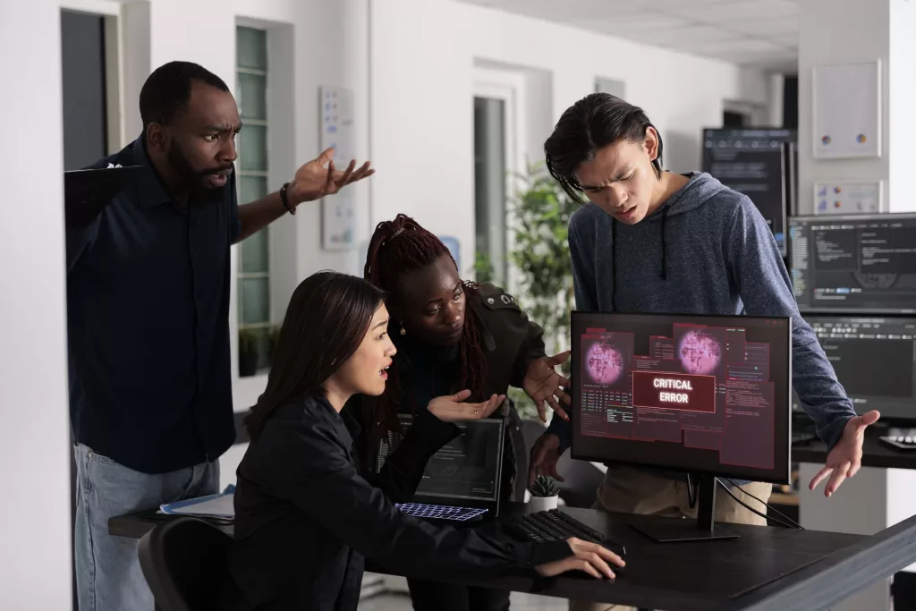 Team of it programmers having web server hacked, looking at critical error on computer monitor in big data office. Diverse software developers trying to solve hacking problem, firewall security.